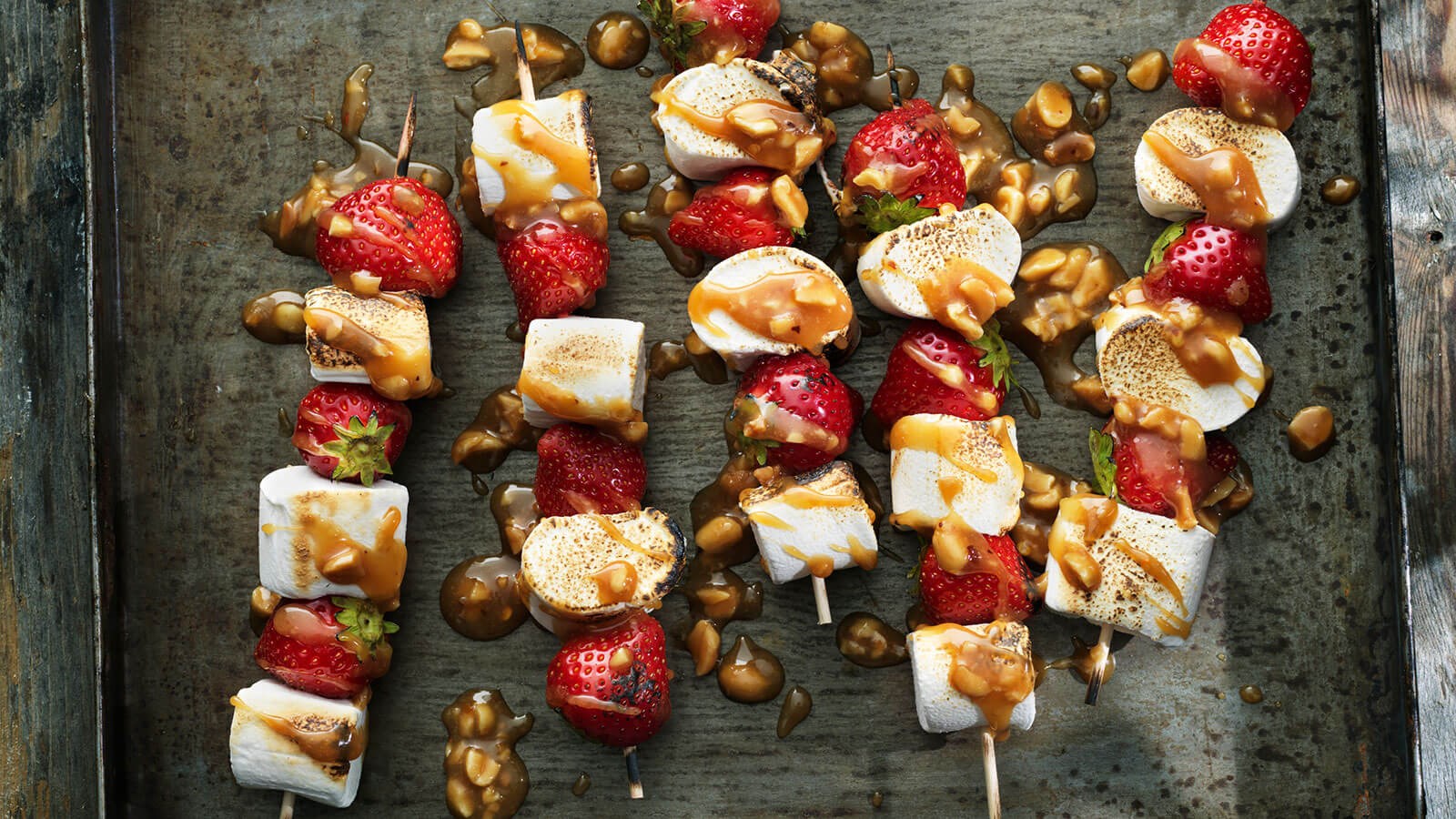 Skewers with strawberries and marshmallows drizzled with caramel sauce
