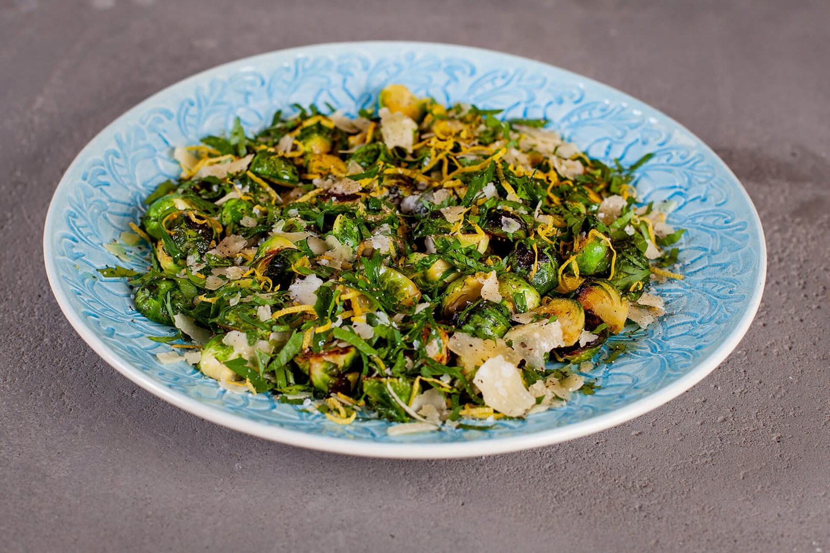 Fried brussels sprouts with gremolata and parmesan on a blue serving dish
