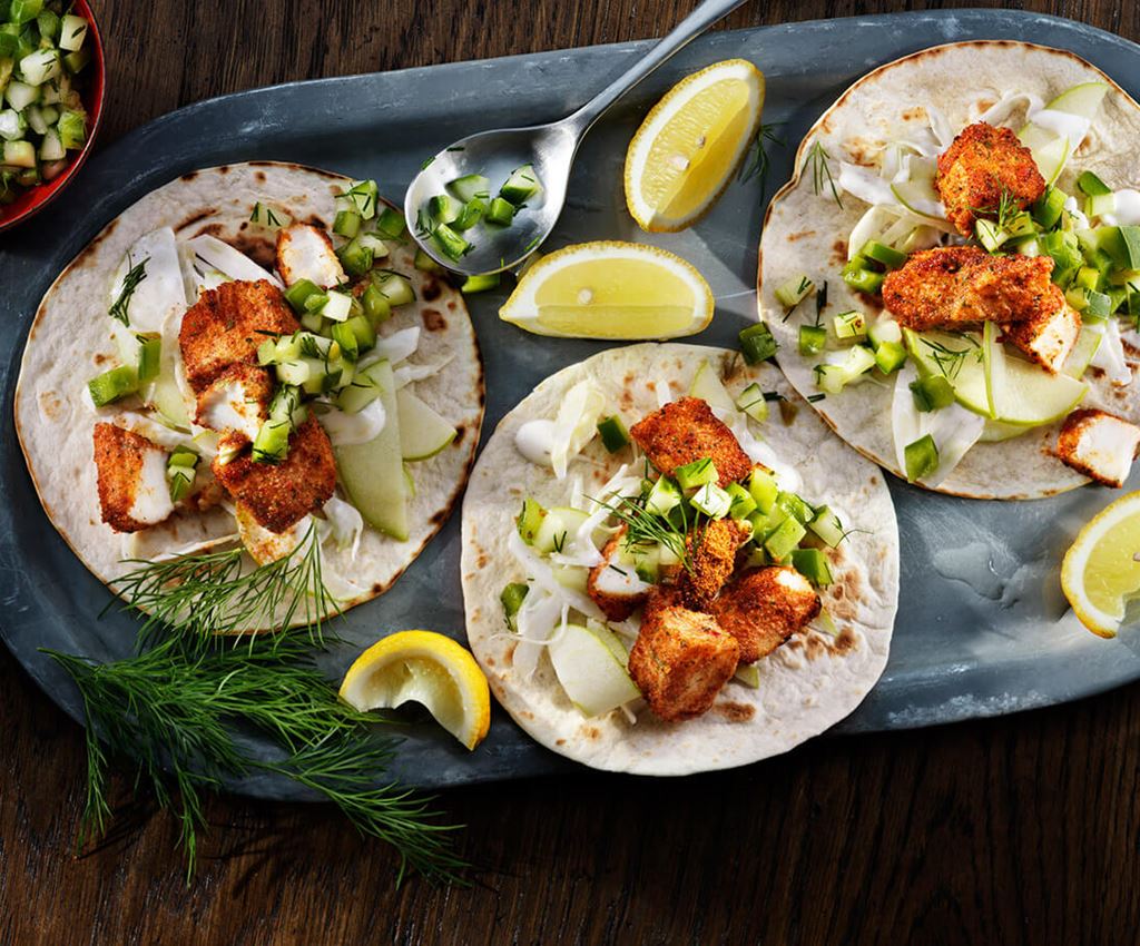 Three fish tacos served on a tray