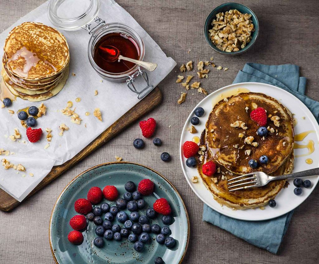 Vegan pancakes with raspberries, blueberries, maple syrup and pecans