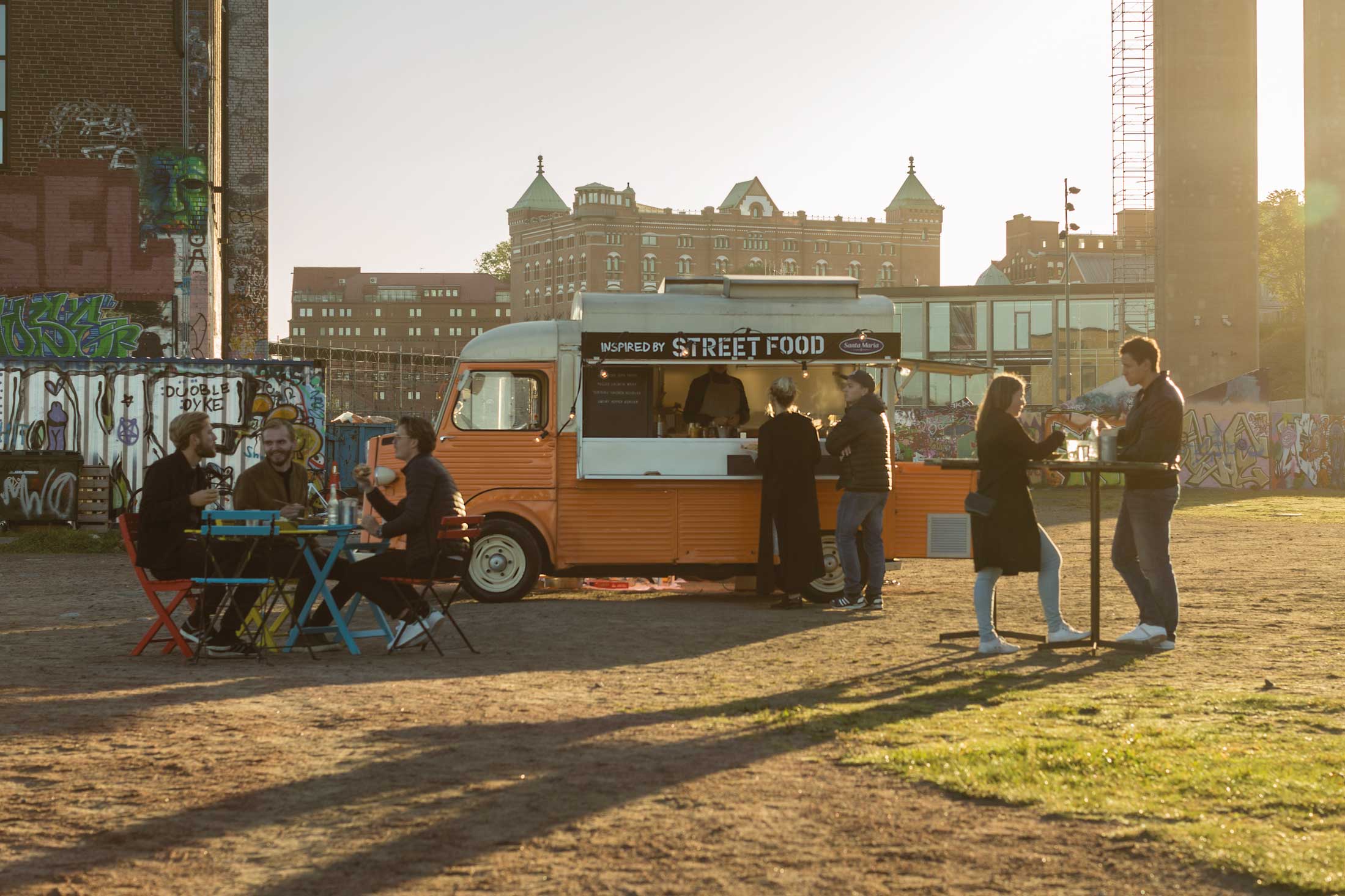 Folk spiser foran en food truck.