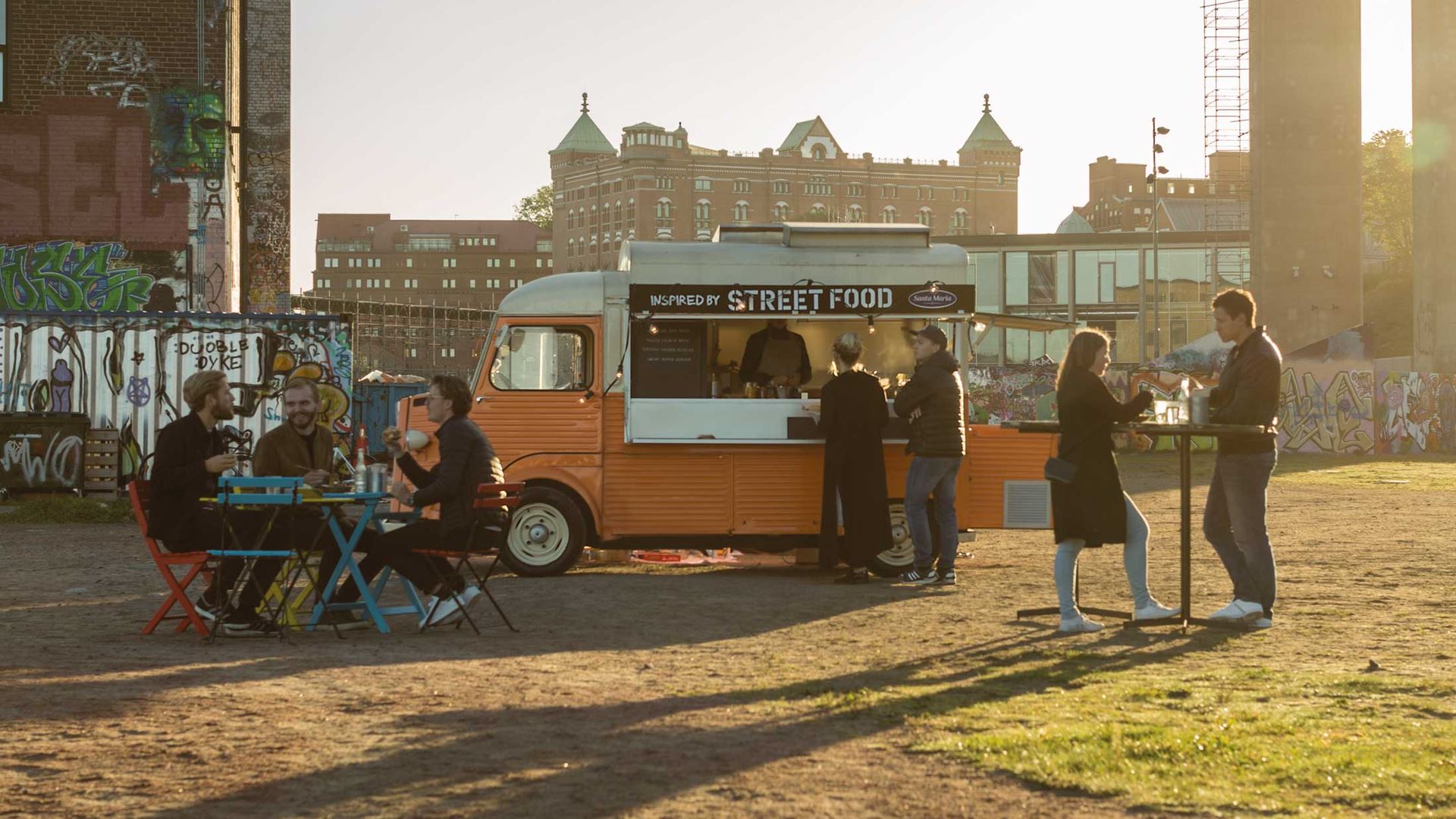 Människor äter och umgås framför en food truck vid Röda Sten i Göteborg.