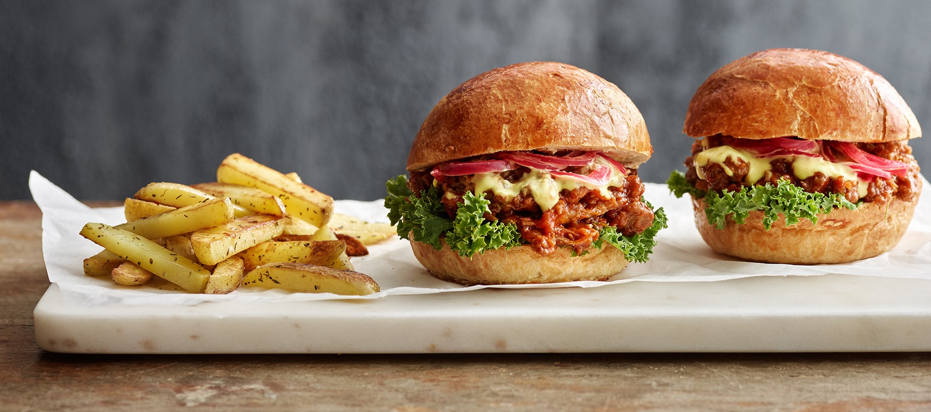 Divi burgeri ar kartupeļiem uz galda