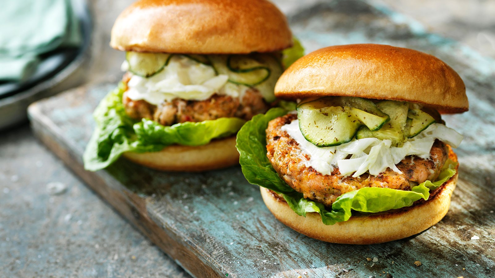 Two salmon burgers in bread with pickled cucumber and fennel salad