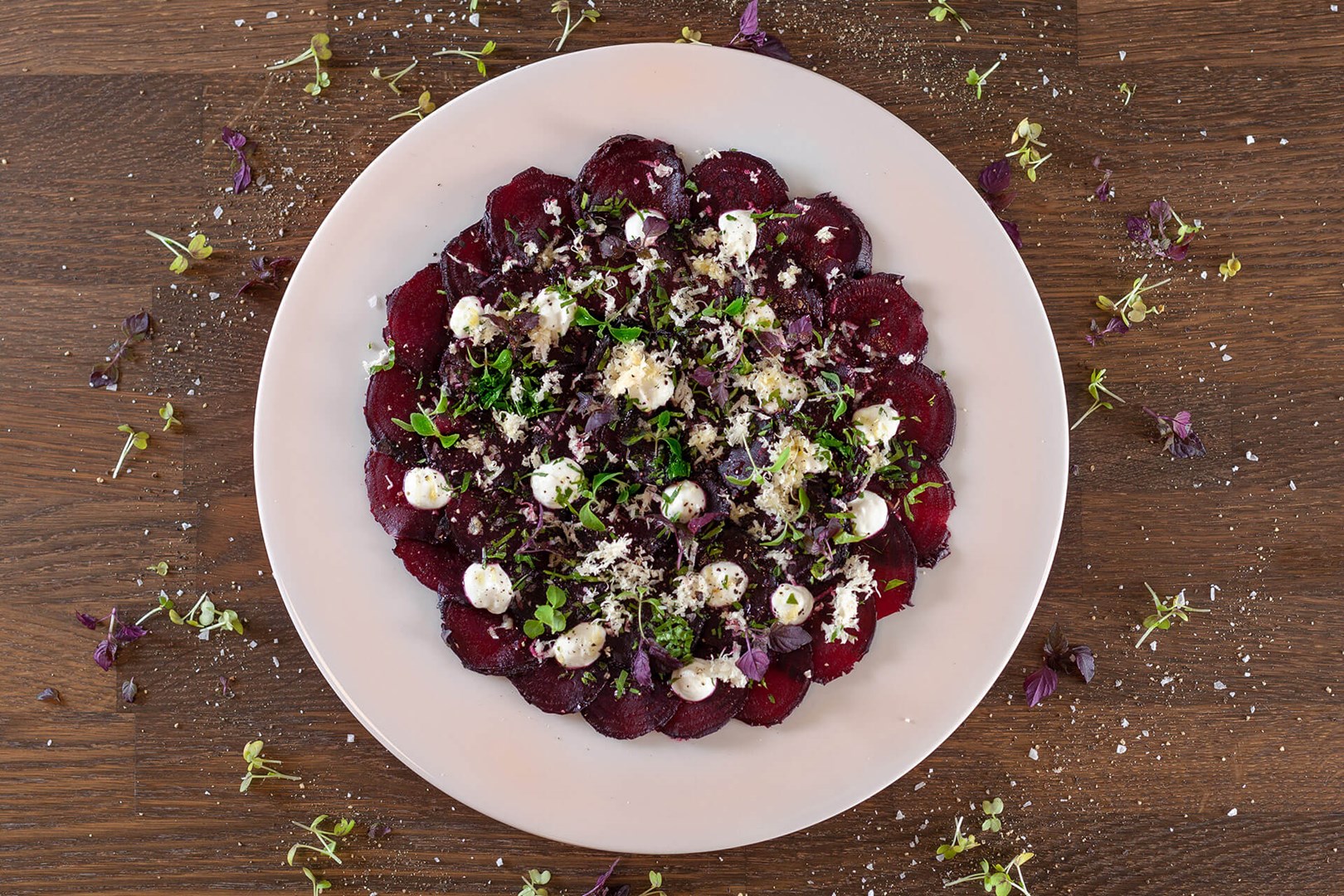 White plate with thinly sliced beetroot topped with horseradish & yogurt
