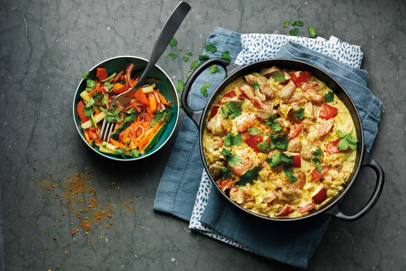 Currykyckling i en gryta med sallad i en skål bredvid