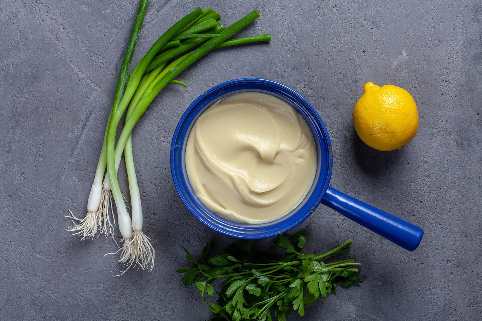 Blue saucepan with celeriac puree surrounded by lemon and garlic