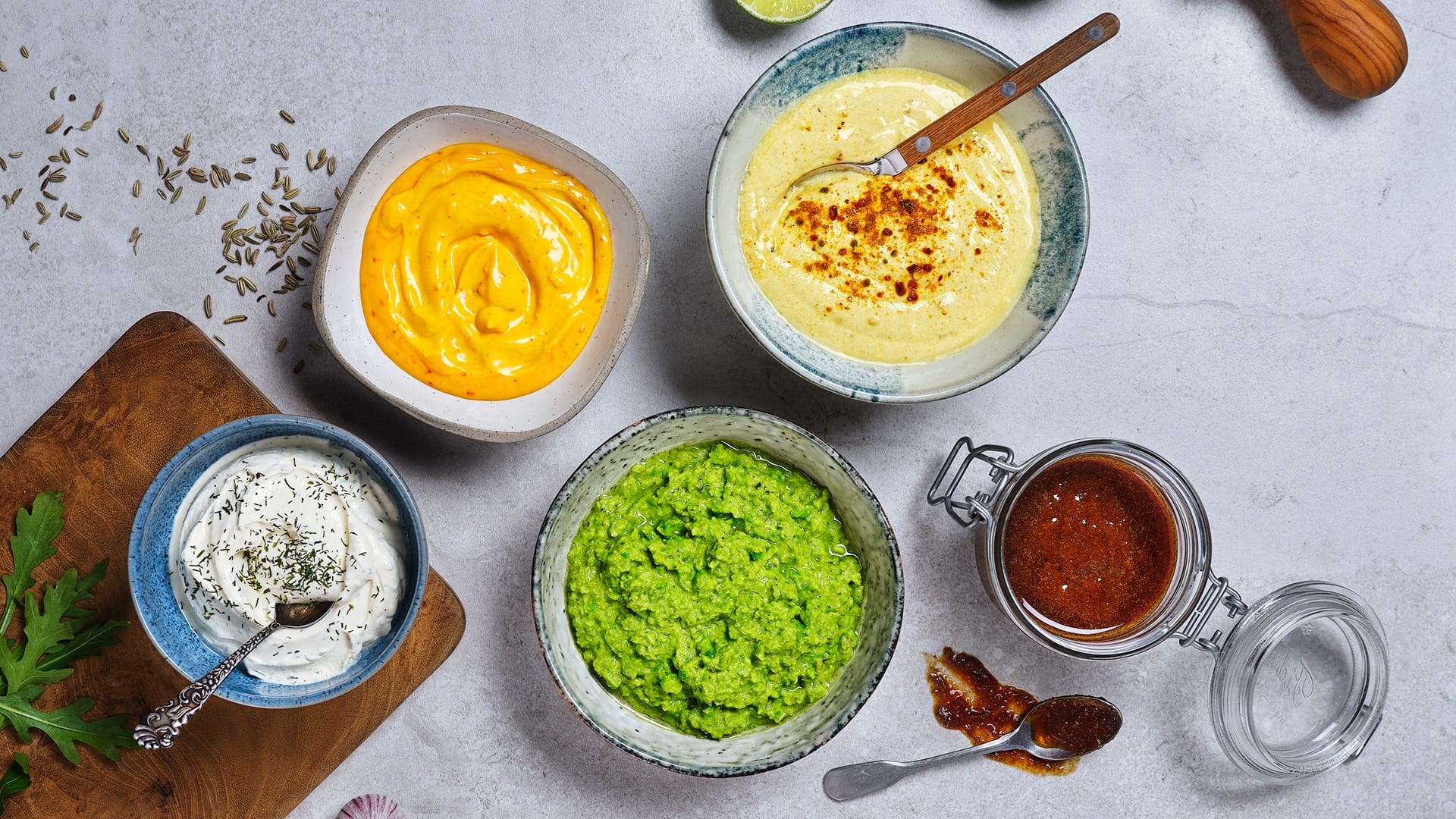 Vijf verschillende sauzen en dressings in kommen en potjes