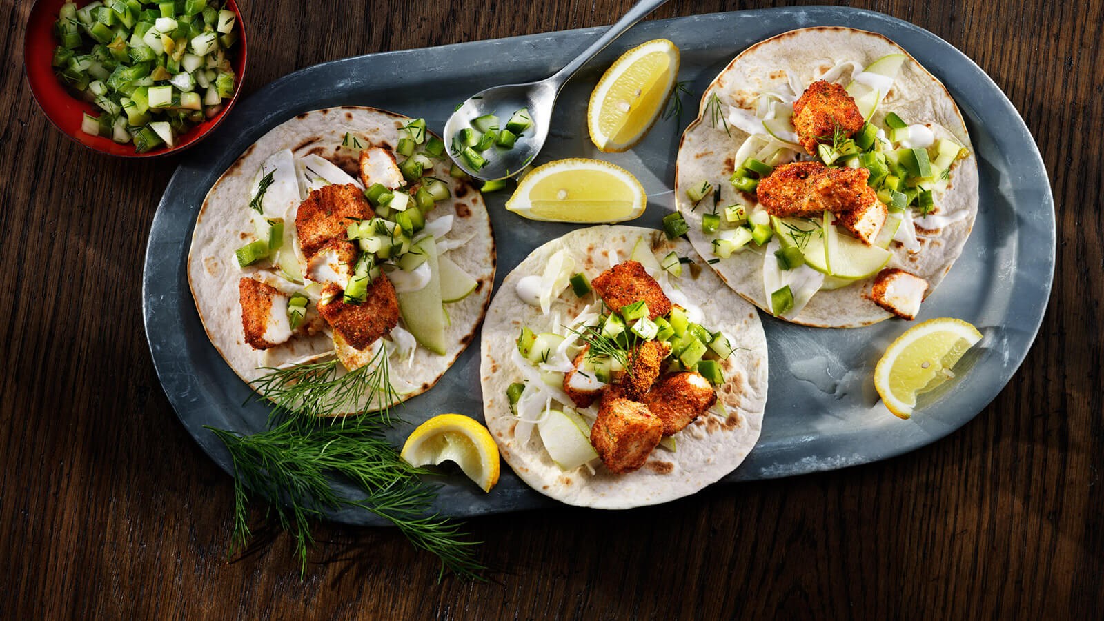 Three fish tacos served on a tray