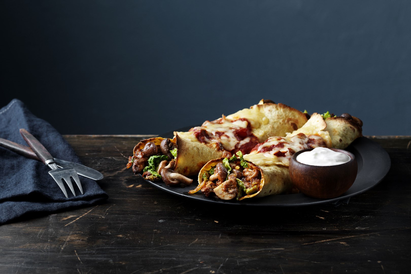 2 vega enchilada's gevuld met champignons en groenten geserveerd op een bord met een bakje zure room