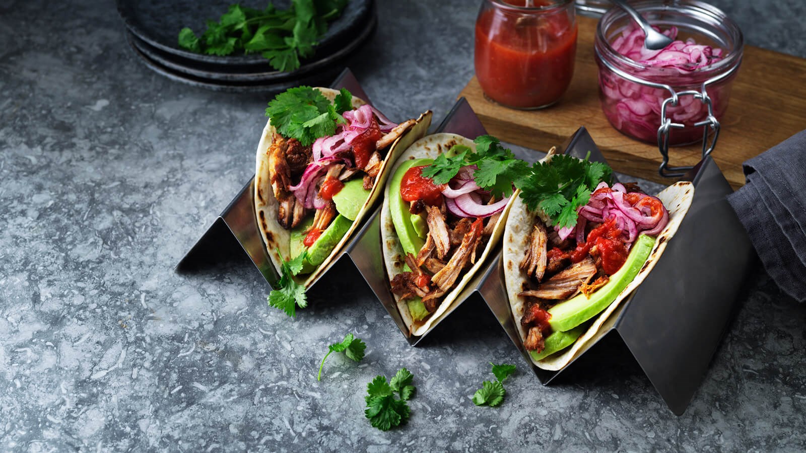 Three pulled pork tacos on a tray