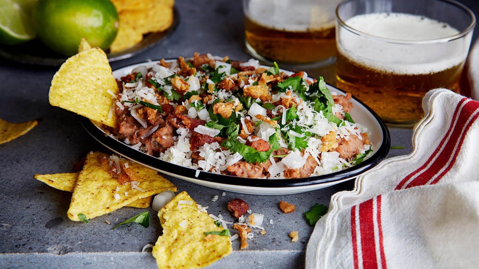 Refried beans with some tortilla chips in a bowl