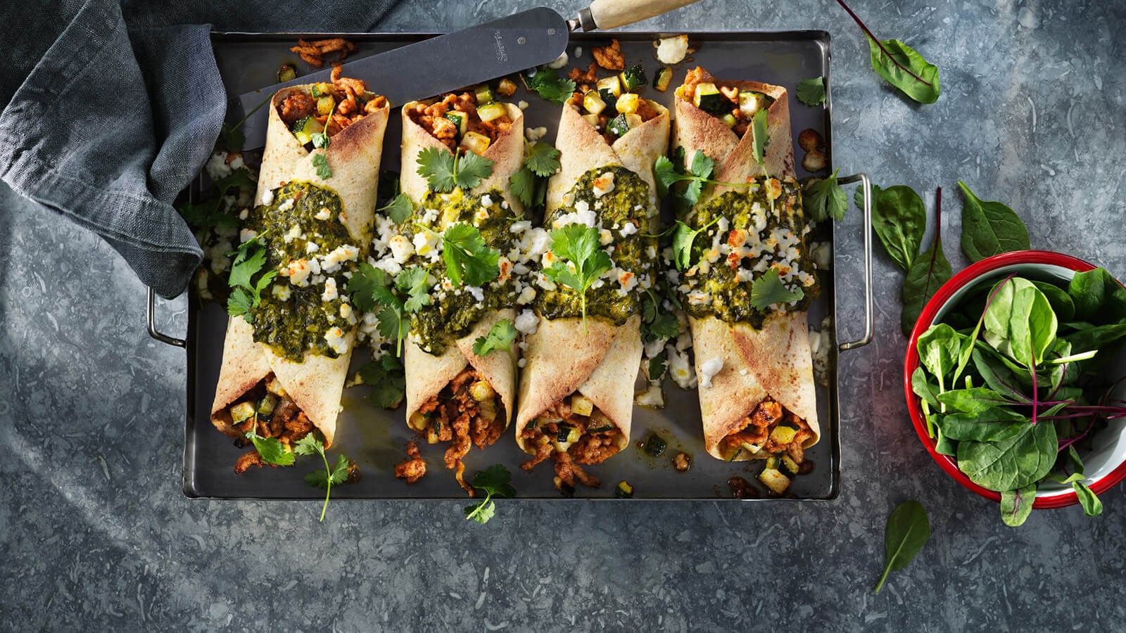 Four spinach and chicken enchiladas on a tray
