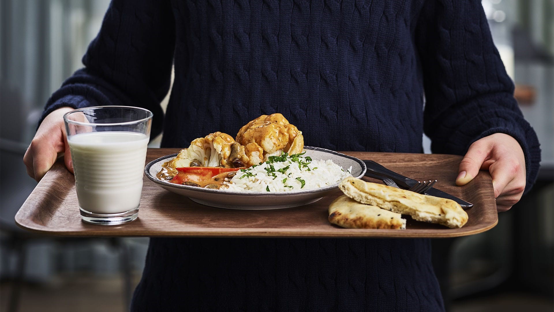 Person håller en bricka med vegetarisk tikka