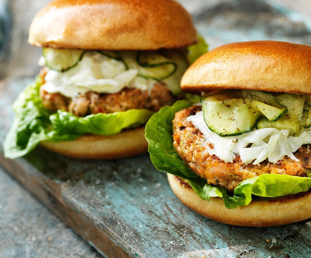 Två grillade laxburgare i bröd med picklad gurka och fänkålssallad