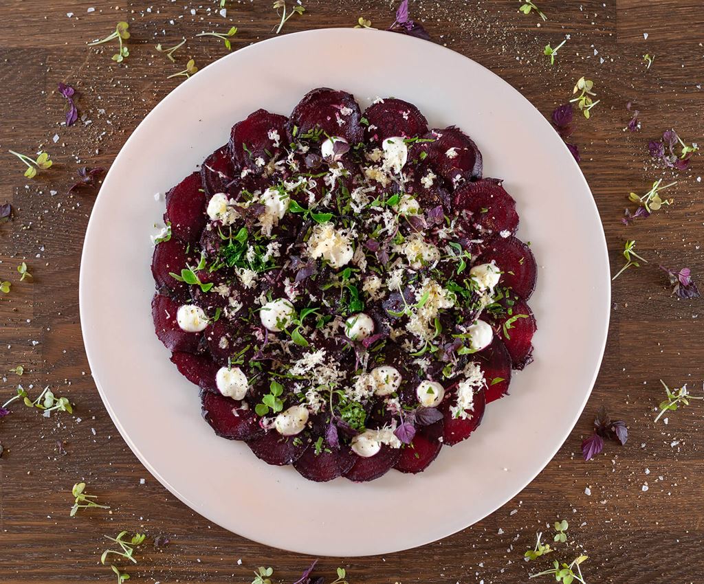 White plate with thinly sliced ​​beetroot topped with horseradish & yogurt