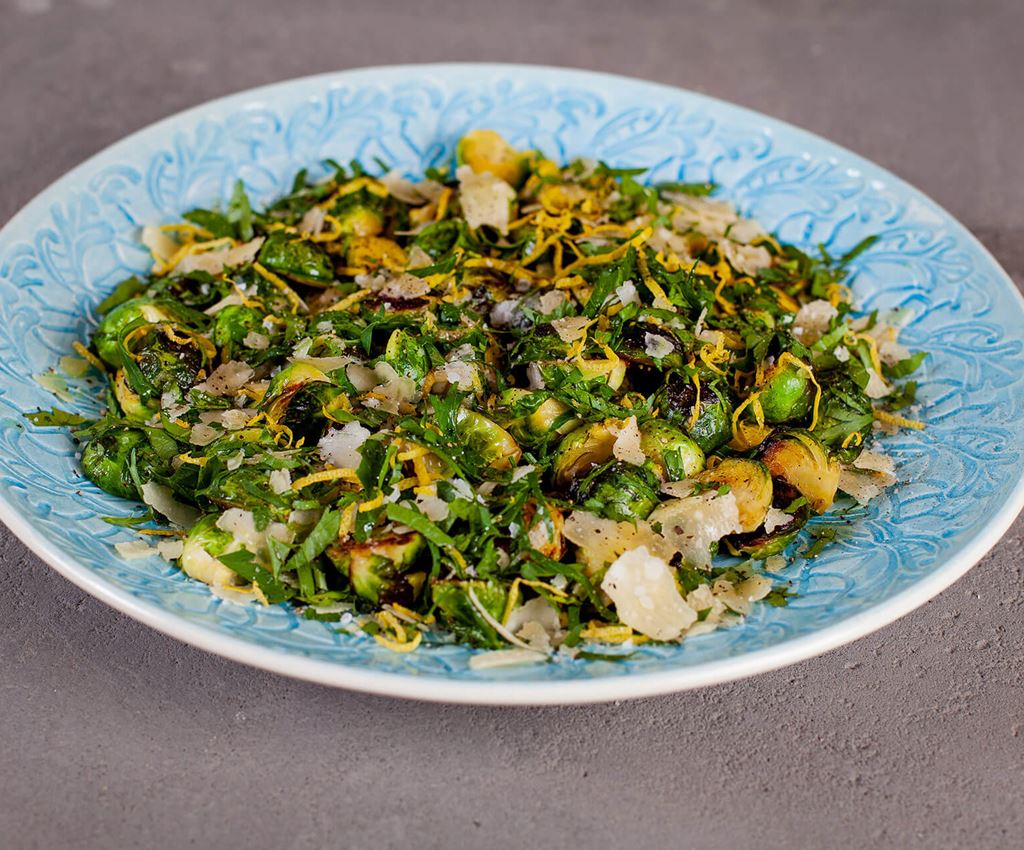 Fried brussels sprouts with gremolata and parmesan on a blue serving dish