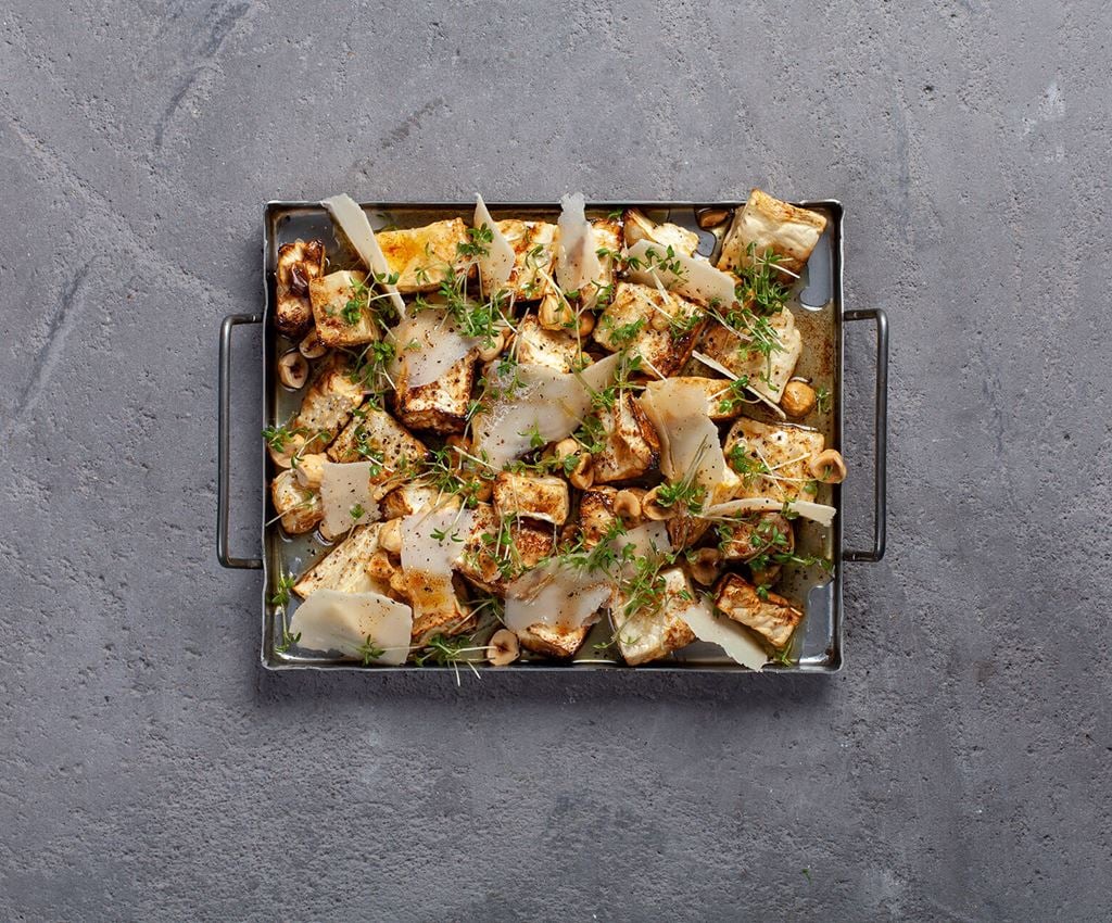 Small oven tray with roasted celeriac topped with parmesan and hazel nuts