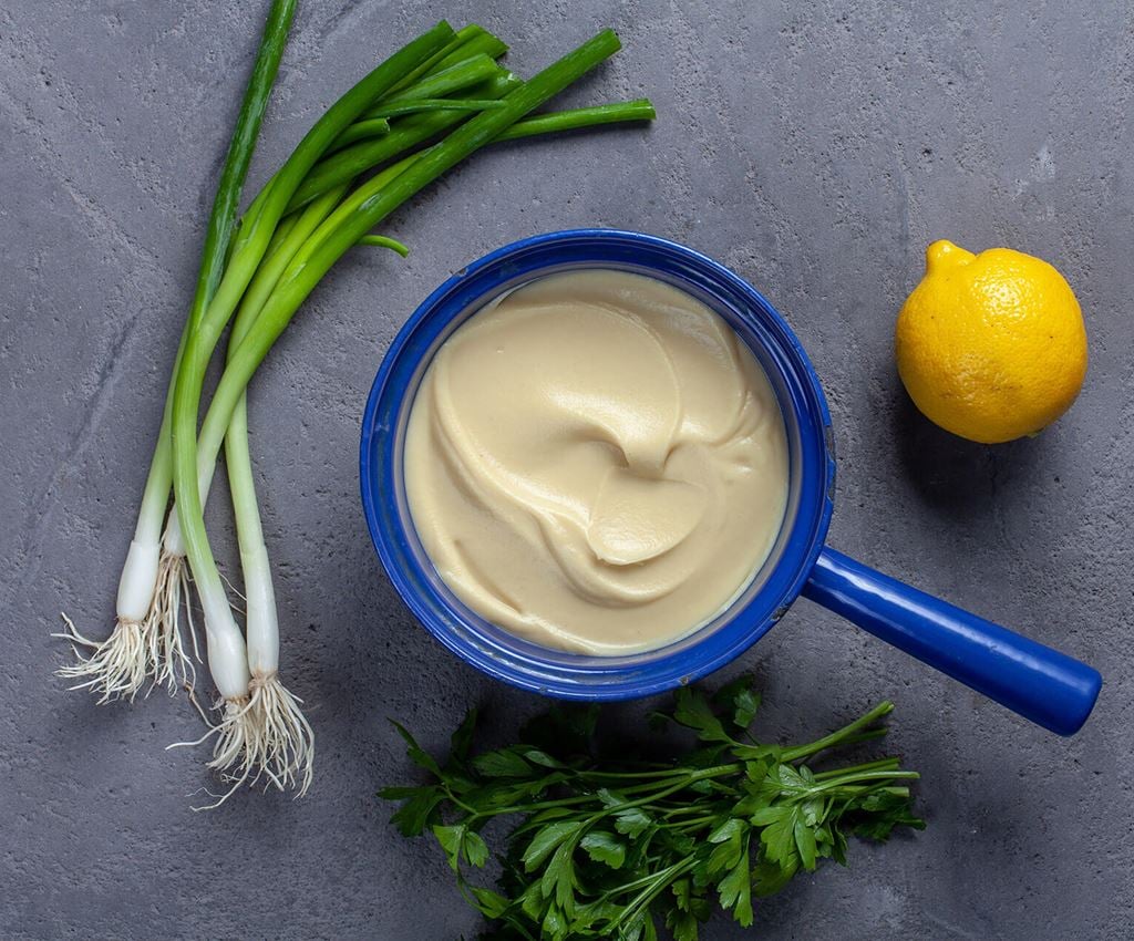 Blue saucepan with celeriac puree surrounded by lemon and garlic