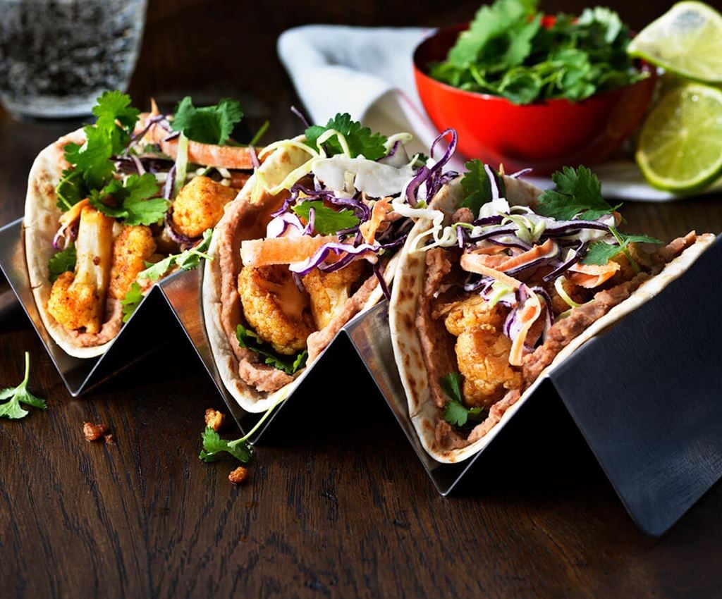 Three cauliflower tacos served on a stand