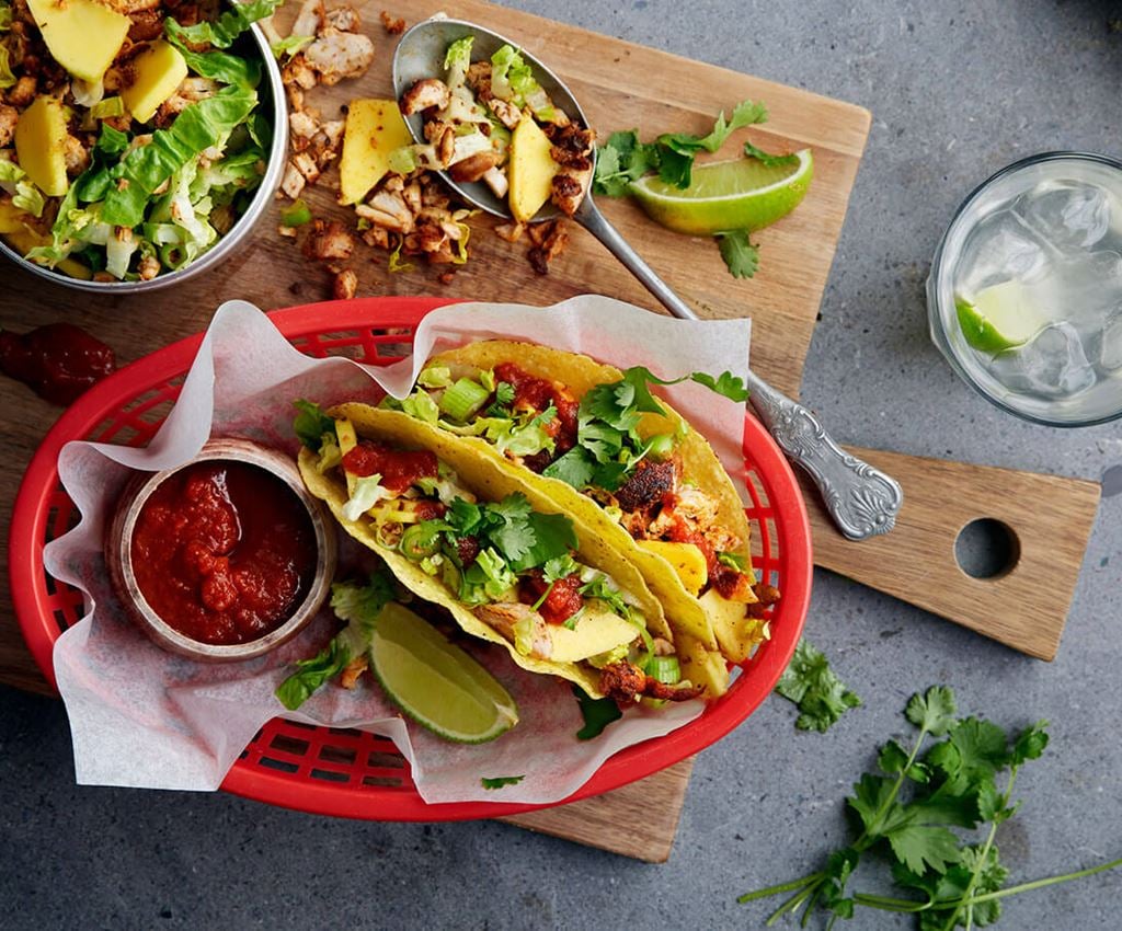 Twee taco's met kip geserveerd omp een rode plastic bord