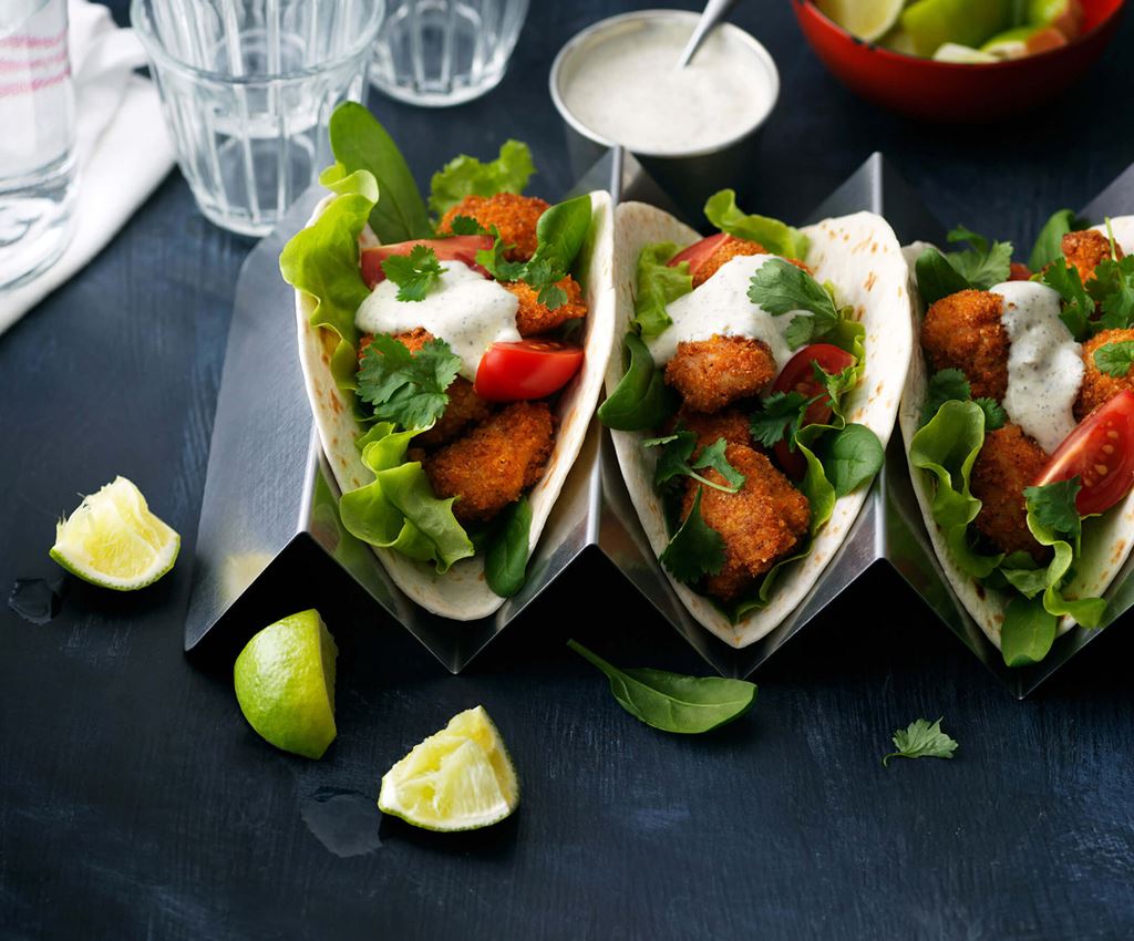 Små mjuka tacobröd med krispga kycklingbitar, sallad och dressing