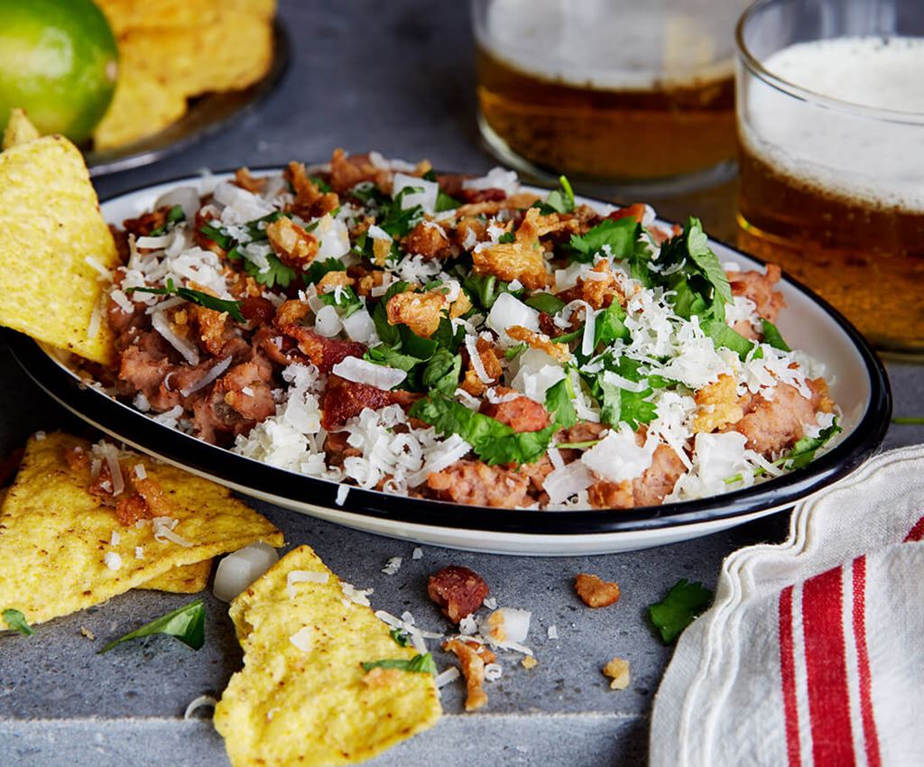 Refried beans with some tortilla chips in a bowl