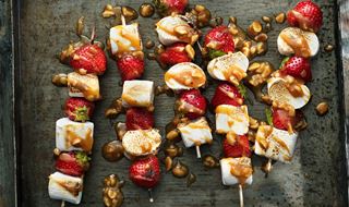 Skewers with strawberries and marshmallows drizzled with caramel sauce