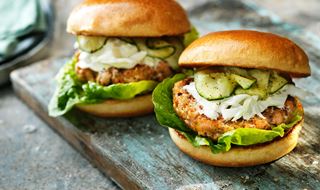 Two salmon burgers in bread with pickled cucumber and fennel salad