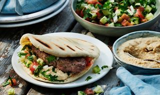 Shish kebab med pitabröd, hummus och hackad tomat- och gurksallad