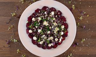 Vitt fat med tunt skivade rödbetor toppade med pepparrot & yoghurt