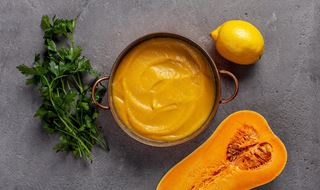 Pumpapuré i en kastrull omgiven av en citron, butternutpumpa och bladpersilja