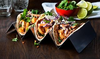 Three cauliflower tacos served on a stand